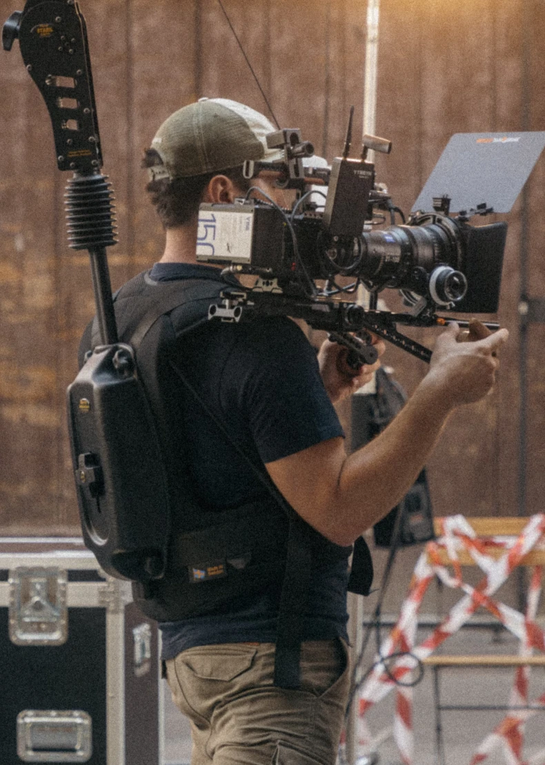 a cameraman with heavy setup in his body and filming